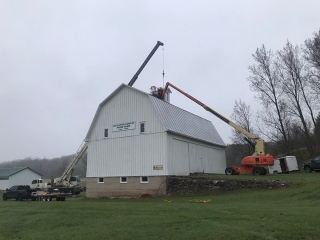 Placing the cupola on the barn roof.